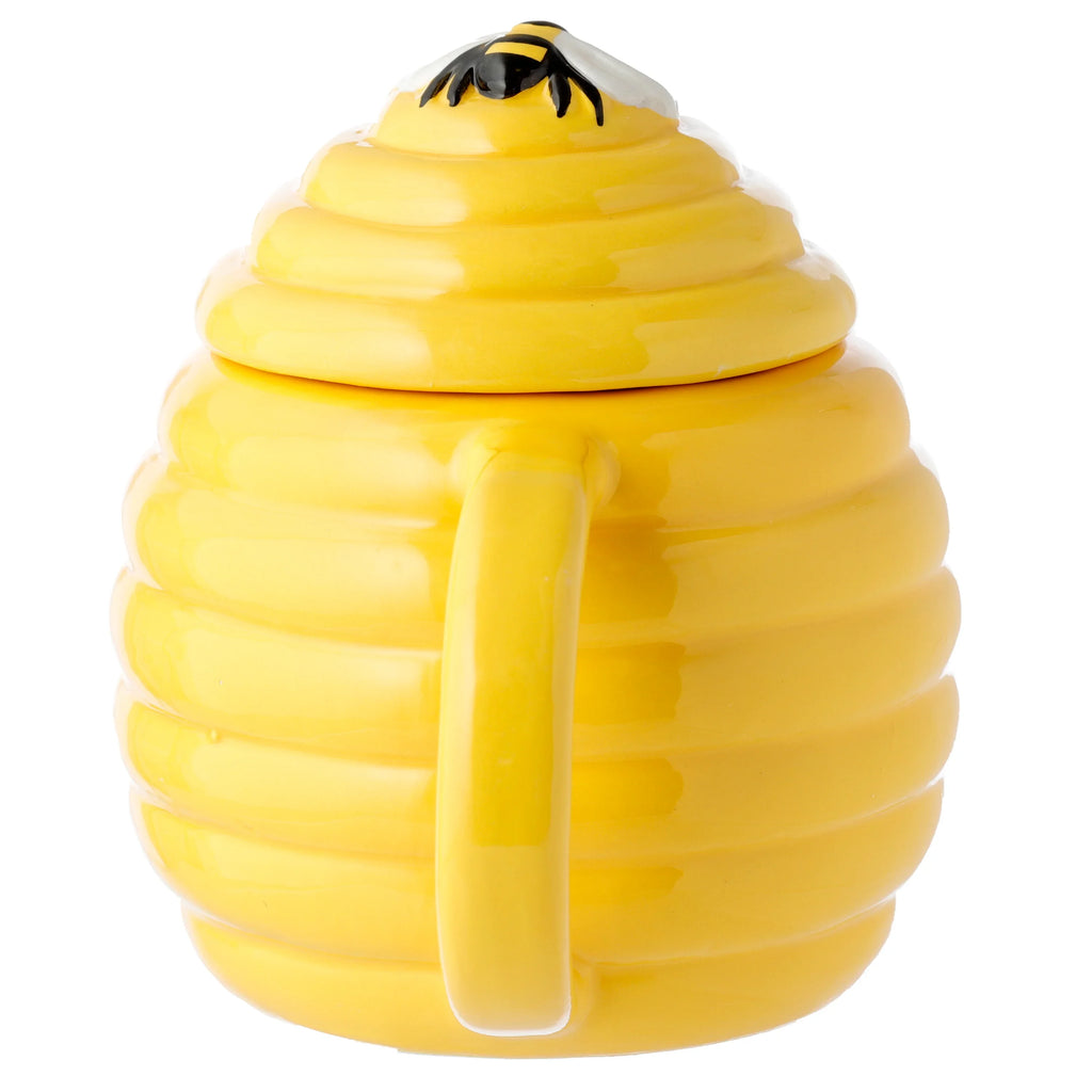 Yellow ceramic beehive-shaped mug, showing its handle and a bee detail on the ribbed lid.
