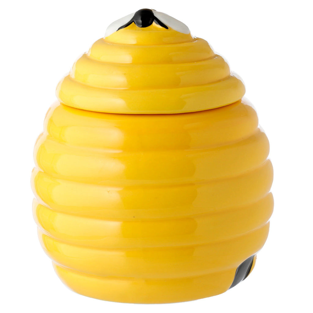 Angled view of a bright yellow, glossy ceramic beehive-shaped mug with a lid. A black and white bee detail is on the lid, and a black accent is visible near the base.