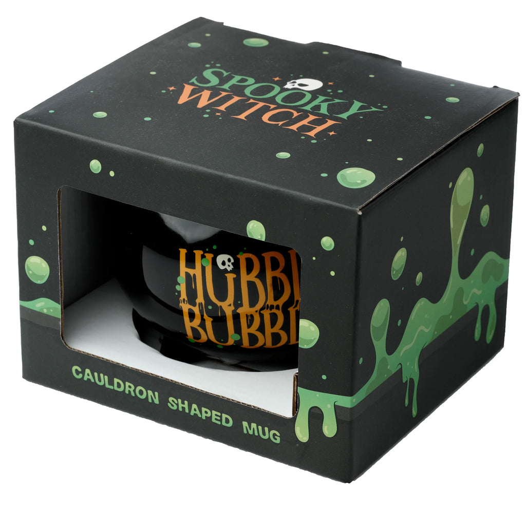 Angled view of a black cauldron-shaped ceramic mug in its black packaging, showing Spooky Witch with a skull graphic and green slime on the box, and Hubble Bubble in orange text on the mug visible through the window.