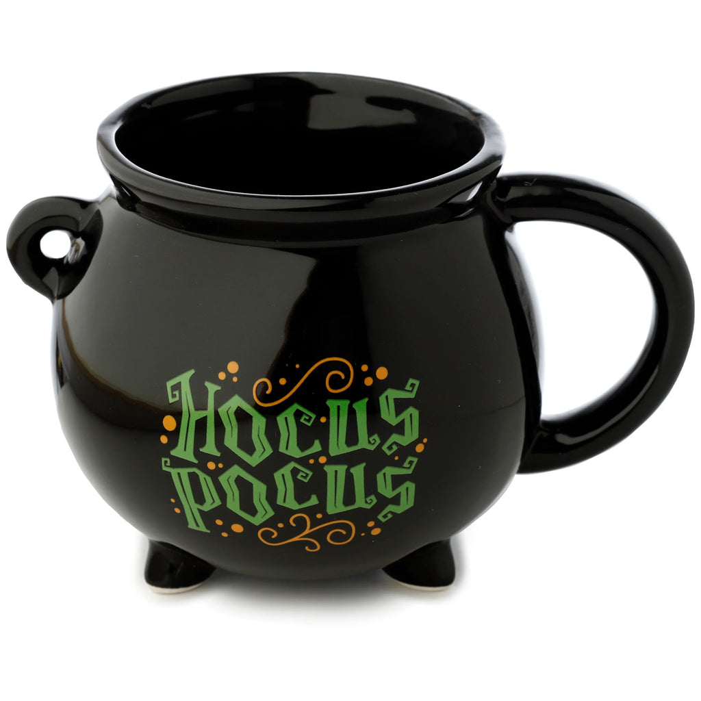 Angled front view of a black ceramic cauldron-shaped mug with green 'Hocus Pocus' text, orange decorative accents, a loop handle, and three small feet.