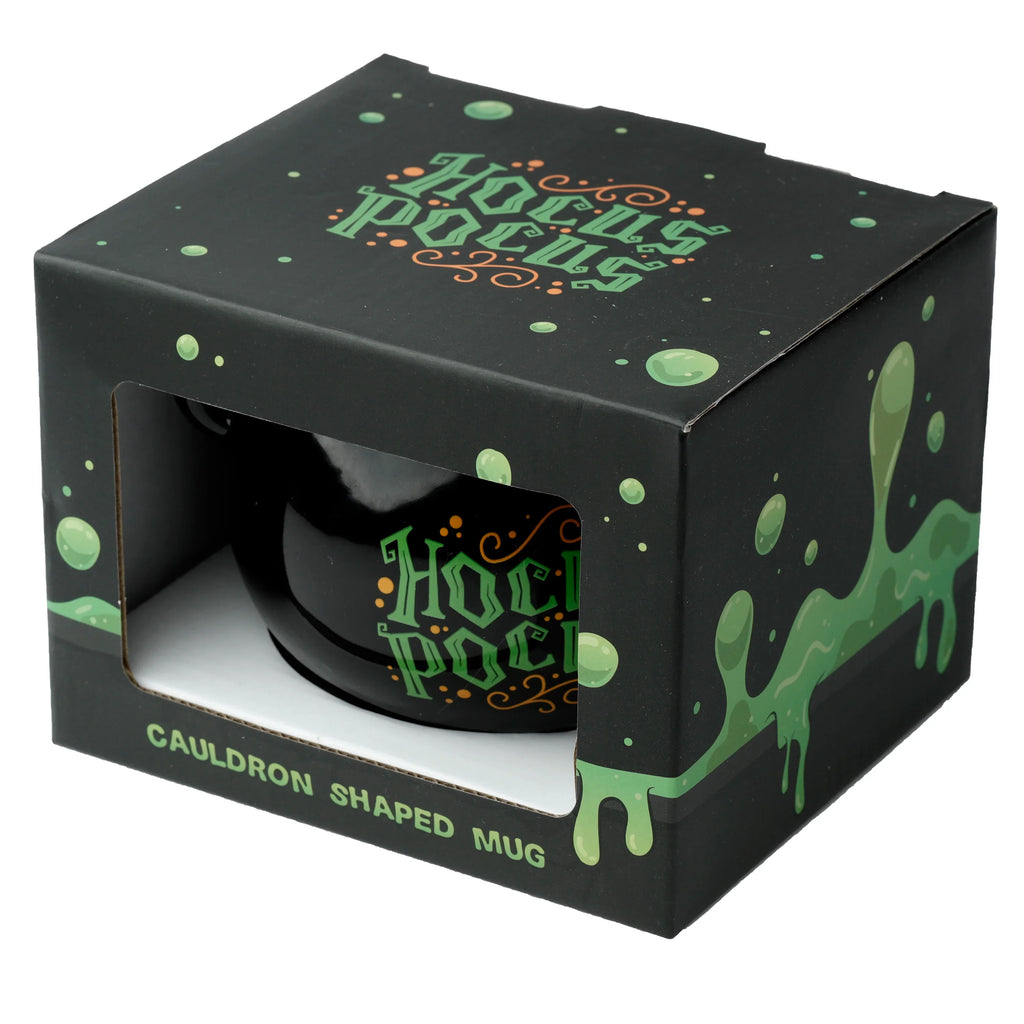 Angled view of a black Hocus Pocus cauldron ceramic mug, featuring green 'Hocus Pocus' text, showcased in its black box with a front window and green slime design.