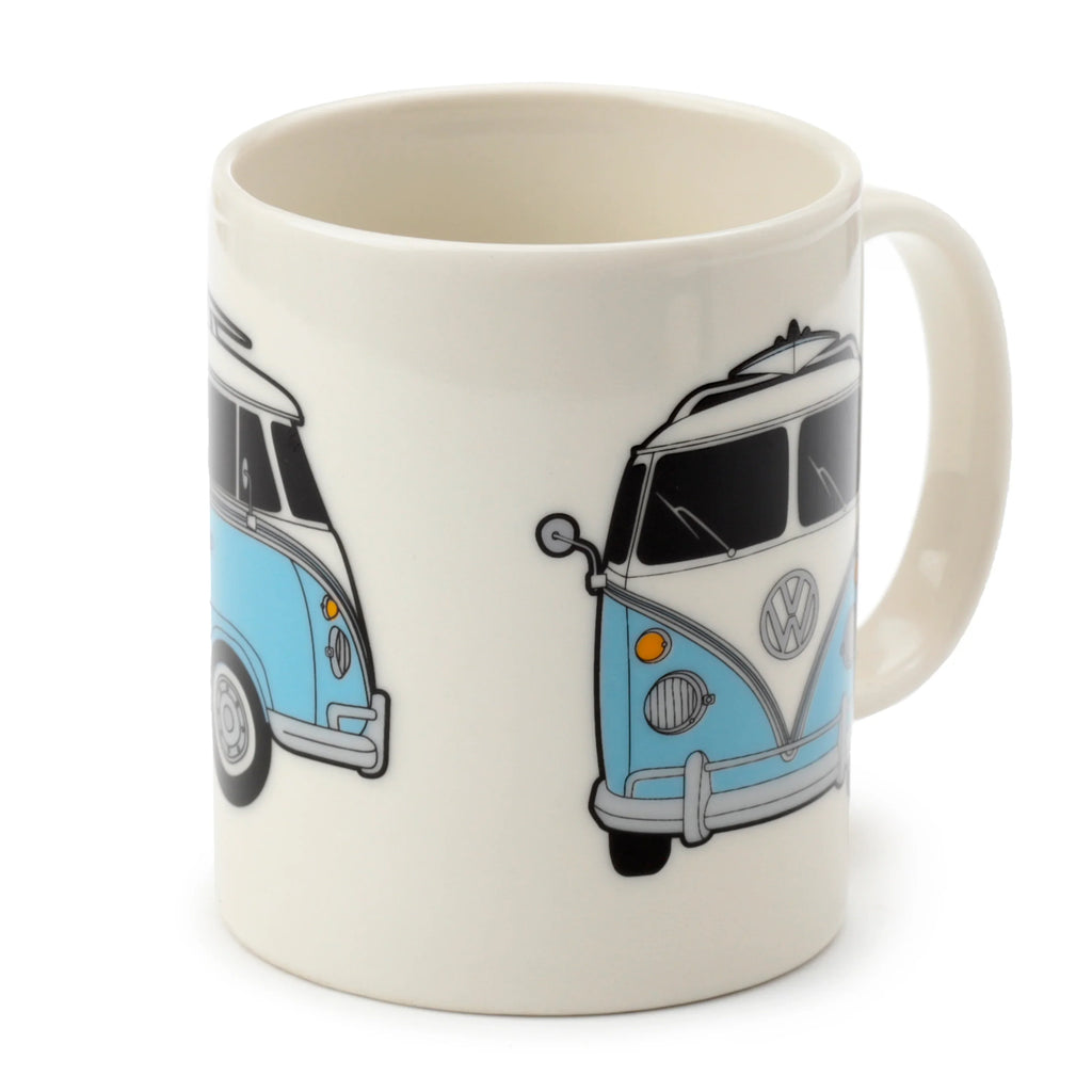 Angled view of a cream porcelain mug, featuring blue and white VW T1 Camper Bus illustrations, with the front of one bus and an angled view of another visible, alongside the mug's handle.