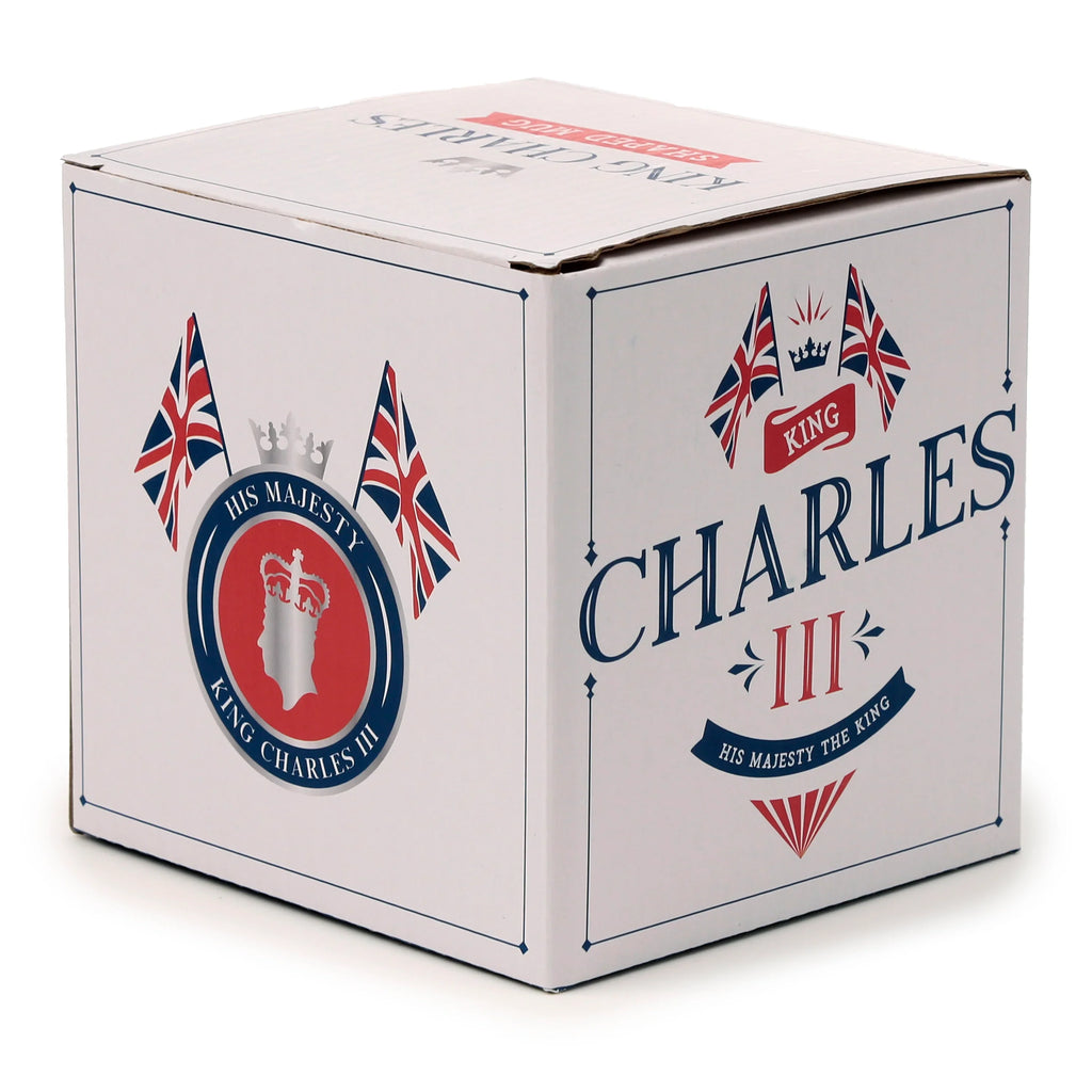 Angled view of a white cardboard box for a Ceramic Shaped Head Mug, adorned with King Charles III commemorative branding. The packaging features blue and red accents, including Union Jack flags, a silver crown, and a silhouette of King Charles III's head, alongside text such as 'King Charles III' and 'His Majesty The King'.