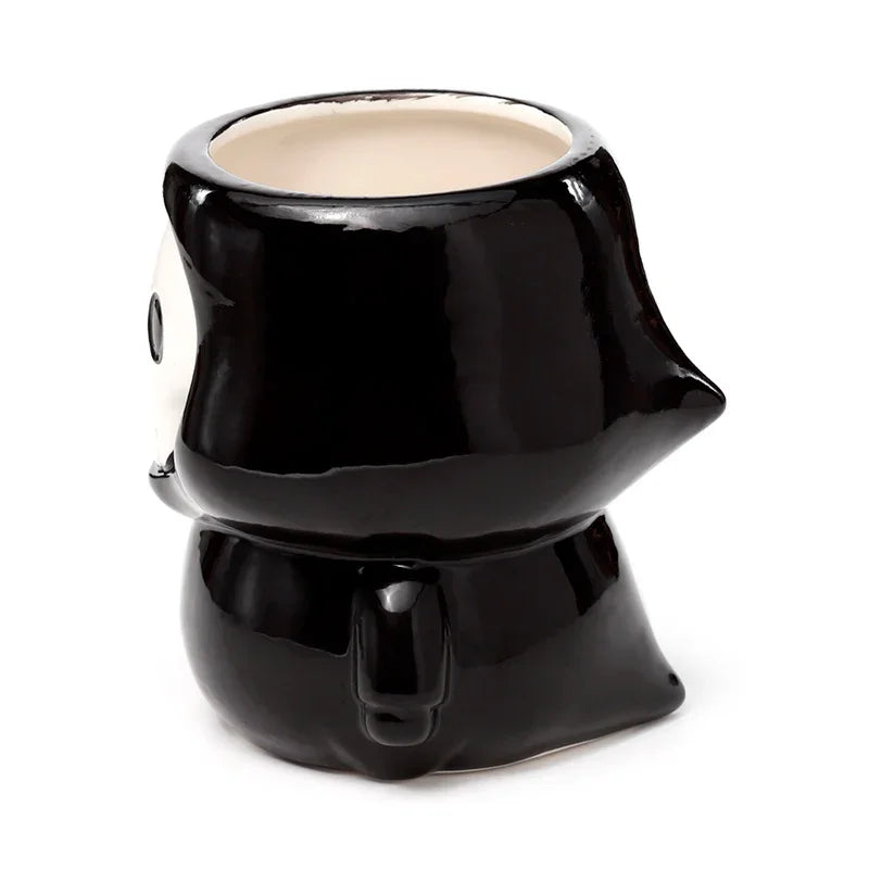 Angled view of a black, glossy, novelty shaped ceramic mug, showing its rounded form and a small handle. The inside of the mug is white.