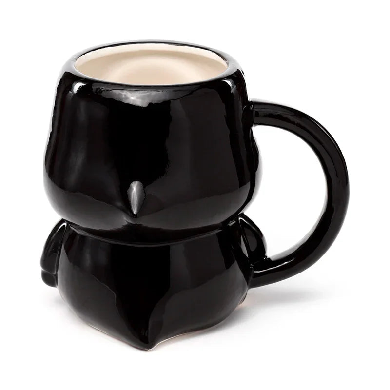 Angled view of a glossy black novelty ceramic mug with a stylised figure shape, a cream interior, and a visible handle.
