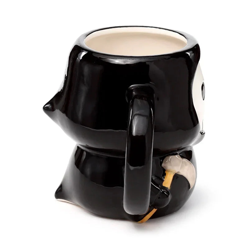 Rear angled view of a glossy black ceramic novelty Skull Boy mug, featuring a hooded, robed figure design, a black handle, and a grey scythe detail. The mug's interior is light cream.