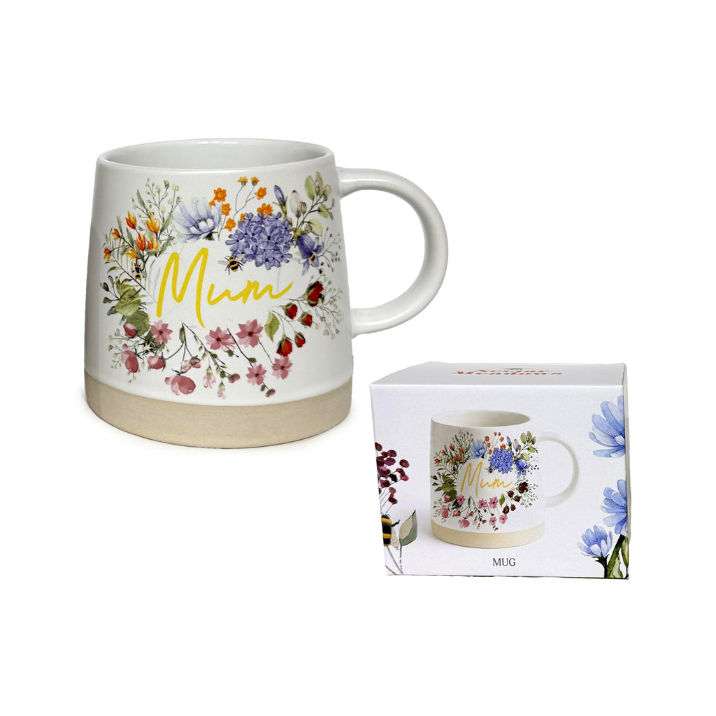 Angled view of a white tapered stoneware mug, featuring a colourful floral wreath design with the word 'Mum' in yellow script, and a natural unglazed base. A matching white product box is shown beside it.