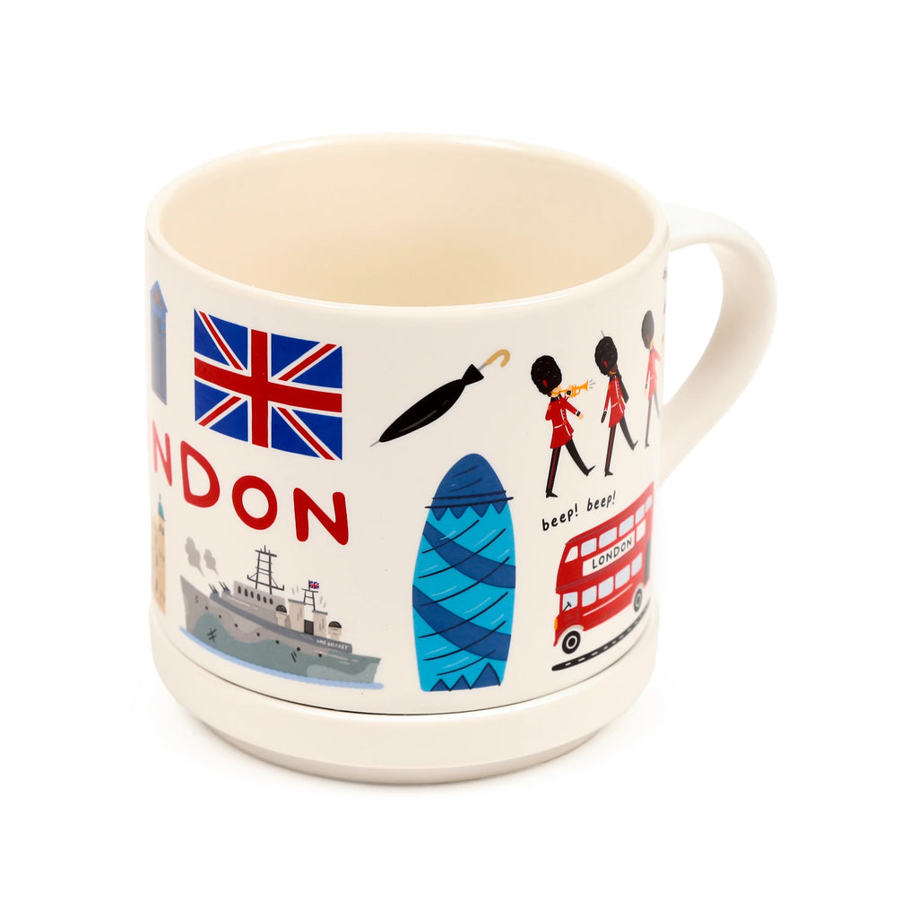 Angled view of a cream porcelain London souvenir mug, featuring colourful illustrations including the Union Jack, a red double-decker bus, The Gherkin, Queen's Guard figures, and an umbrella, sitting on its white coaster lid.