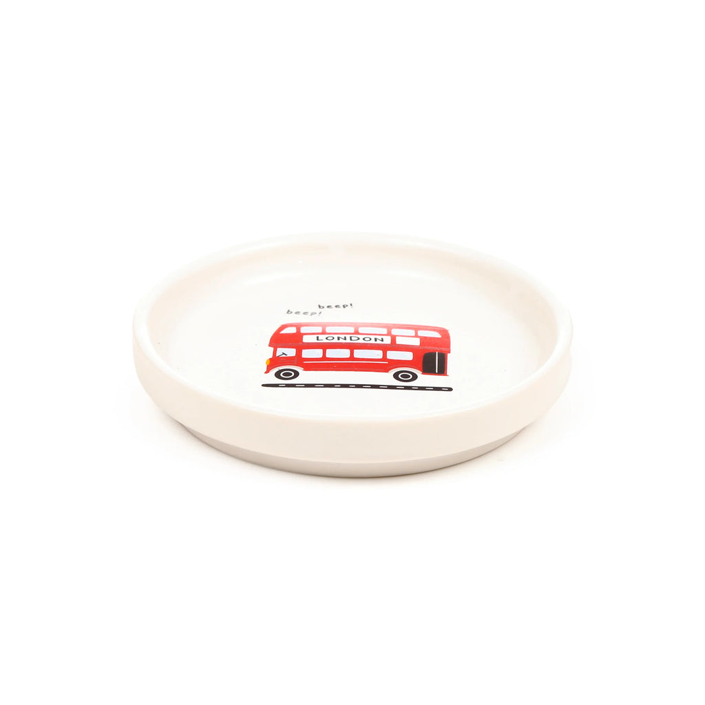 Angled view of a white porcelain coaster lid, decorated with a red London double-decker bus illustration and 'beep! beep!' text.
