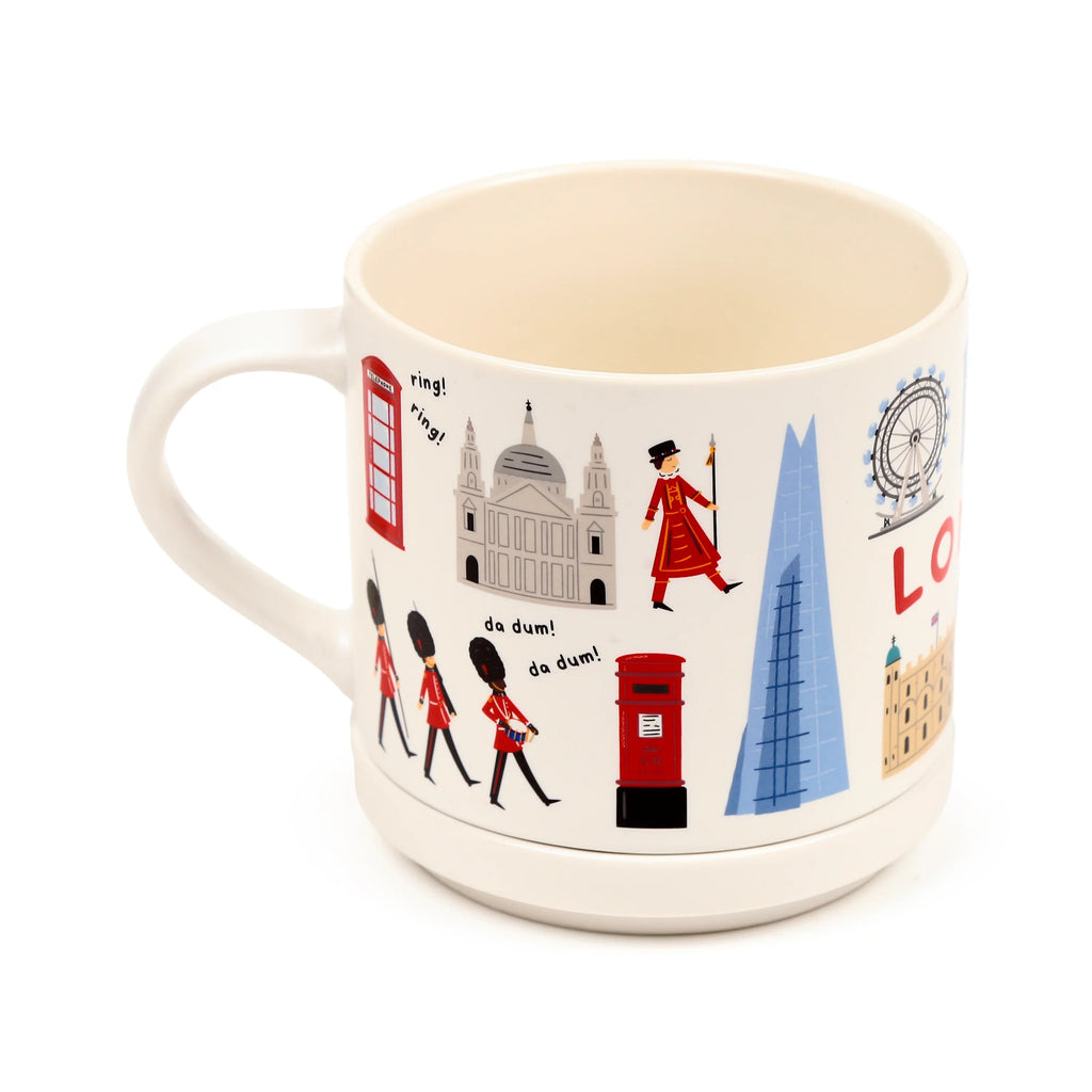 Angled view of a cream porcelain mug with a London souvenir design, featuring detailed illustrations of a red telephone box, St Paul's Cathedral, a Beefeater, marching Queen's Guards, a red post box, The Shard, the London Eye, and the Tower of London. The mug has its handle visible on the left and a cream base.