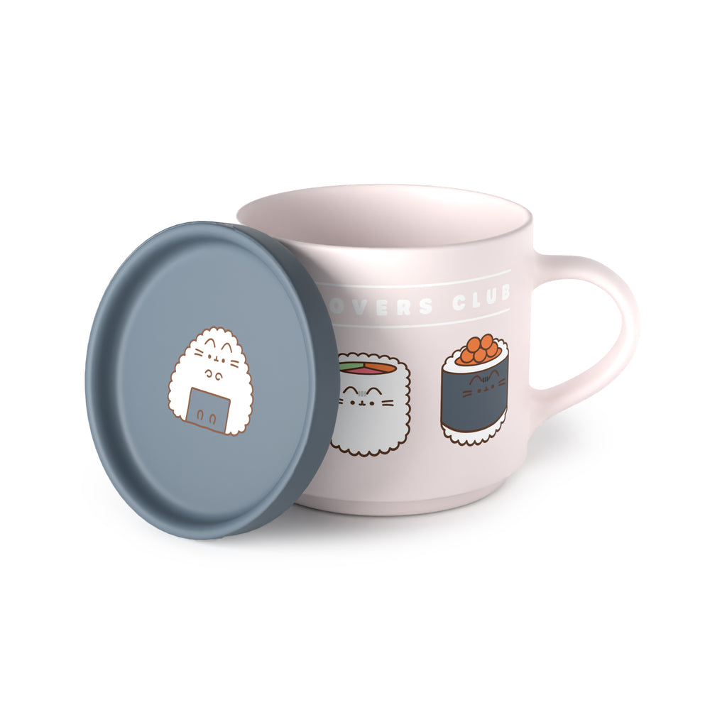 Angled view of a light pink porcelain mug and blue-grey coaster lid set. The mug's visible side features cartoon cat sushi designs and partial 'OVERS CLUB' text, with its handle shown. The coaster lid, leaning against the mug, displays a cartoon cat onigiri design.