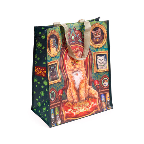 Angled view of a reusable shopping bag featuring a fluffy ginger cat on a red ornate chair. The dark green bag is decorated with smaller framed cat portraits and a celestial pattern of stars and moons on the side, complete with beige woven handles.
