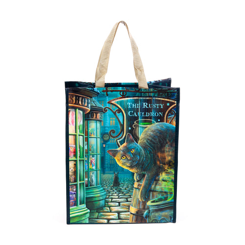 Front view of a reusable shopping tote bag with beige handles, depicting an illustration of a grey cat with yellow eyes in a dark, mystical street scene featuring a sign for 'The Rusty Cauldron'.
