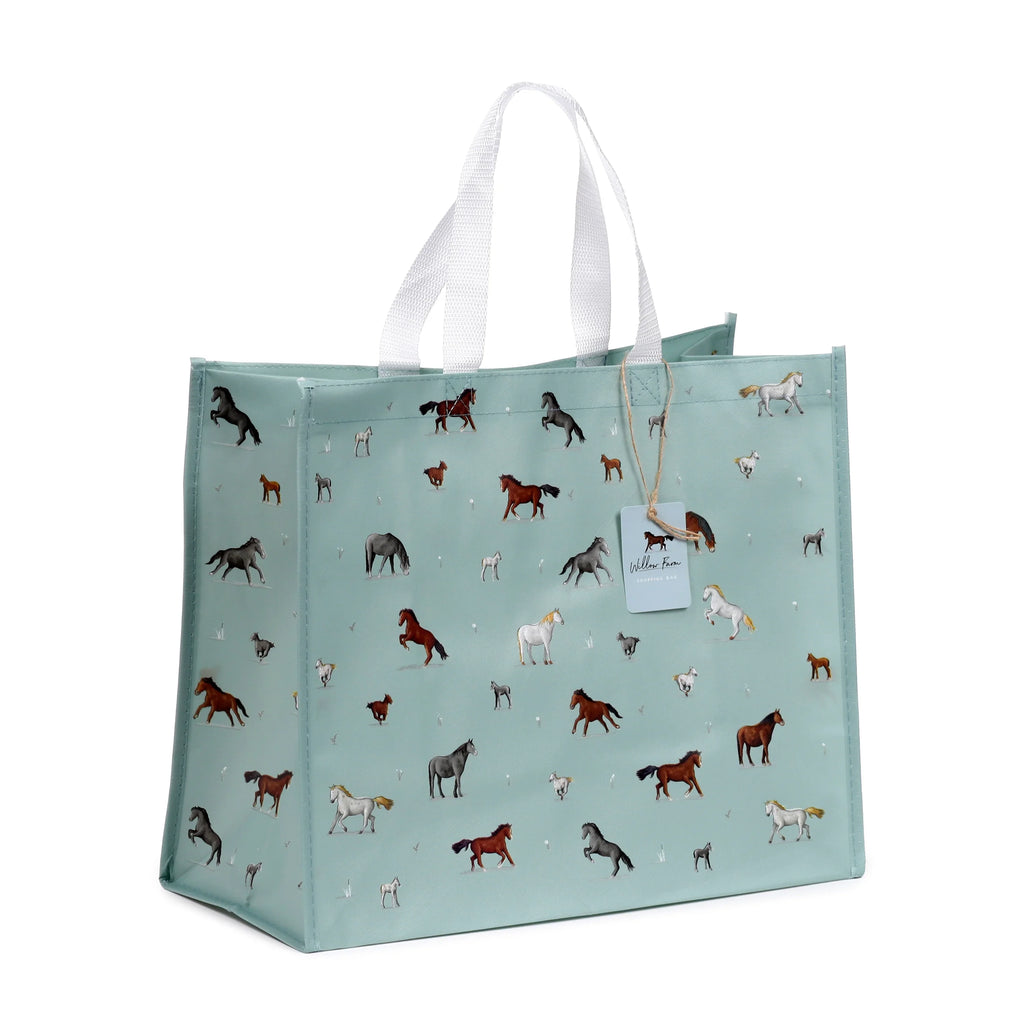 Angled view of a light blue-green reusable shopping bag patterned with various horses, featuring white woven handles and a product tag.
