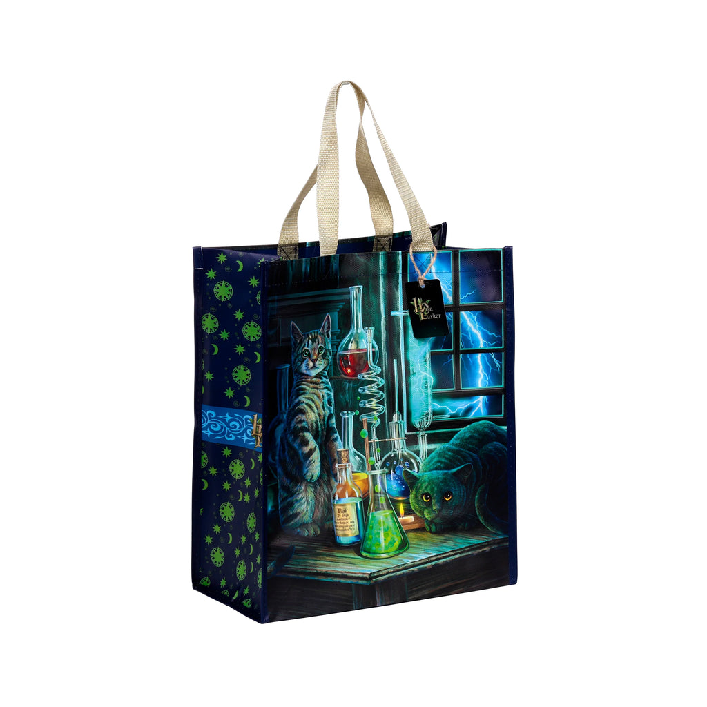Angled front and side view of a reusable shopping bag. The main panel features a Lisa Parker 'Jekyll and Hyde Cats' illustration, depicting a tabby cat standing by laboratory flasks and a dark cat crouching amidst bubbling potions, against a lightning-filled window. The visible side panel is dark blue with neon green celestial patterns; the bag has beige handles.