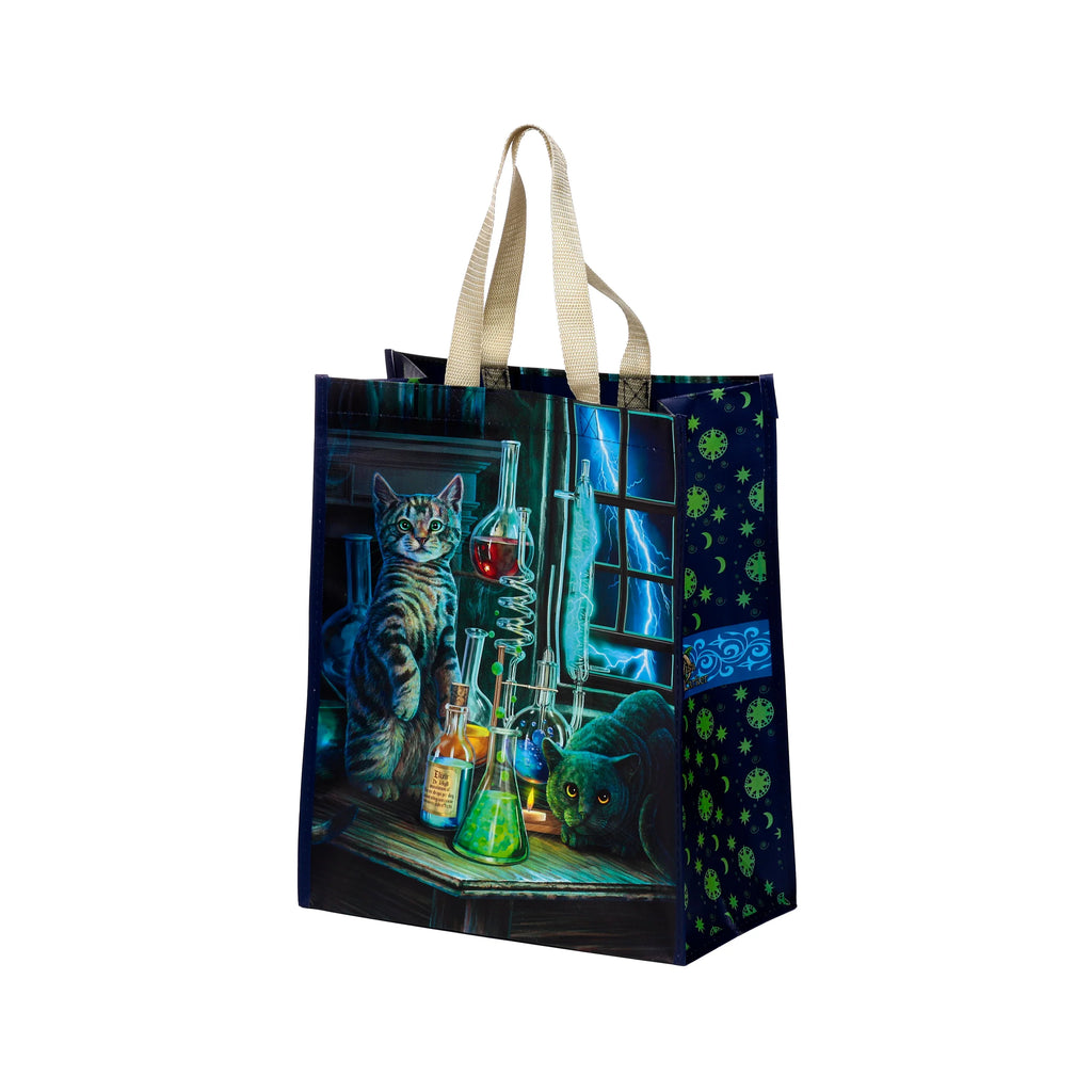 Angled view of a durable reusable shopping bag. The front features a fantasy illustration of a tabby cat and a black cat in a dark laboratory, surrounded by colourful flasks and lightning. The right side displays a dark blue celestial pattern with green stars and moons. It has beige fabric handles.