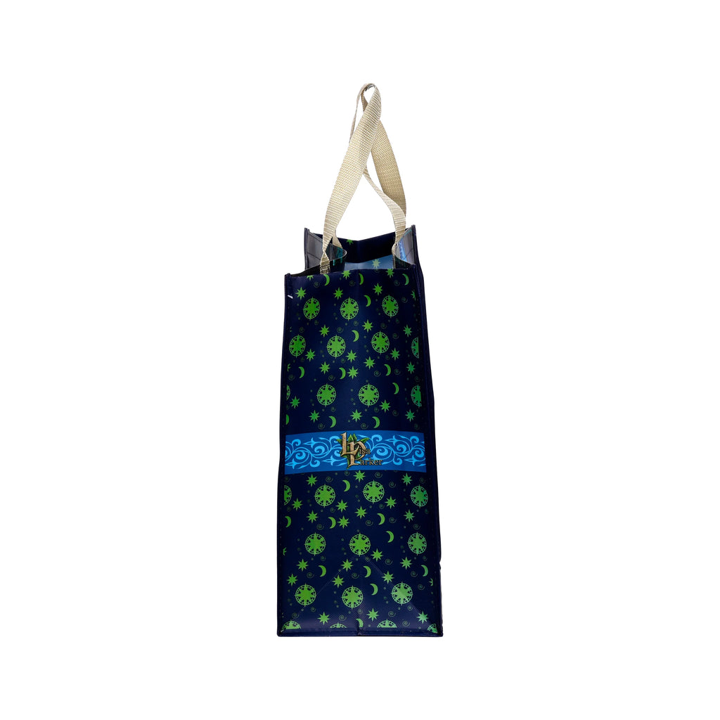Side view of a durable reusable shopping bag, navy with a repeated pattern of green moons, stars, and circular designs. A horizontal blue band displaying 'Lisa Parker' text and ornate swirls crosses the bag. It features beige woven handles.