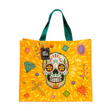 Front view of a durable reusable shopping bag featuring a vibrant Day of the Dead sugar skull design on a yellow background, with green handles and a decorative tag.