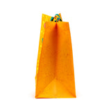 Orange reusable shopping bag, angled view, showing its speckled side and green handles.