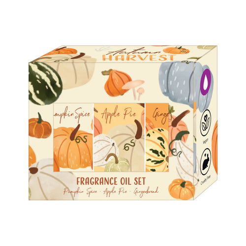 Angled view of an Autumn Harvest fragrance oil set box, featuring pumpkin and gourd illustrations. The box displays the 'Autumn Harvest' title, text for 'Pumpkin Spice', 'Apple Pie', and 'Gingerbread' scents, a purple oil drop graphic, and vegan and cruelty-free logos.