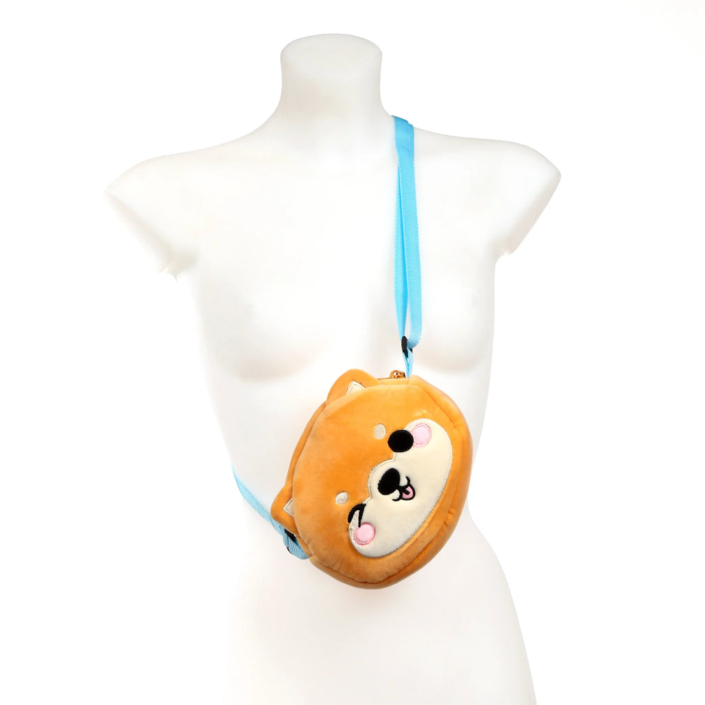 Front view of a plush orange-brown Shiba Inu crossbody bag with an embroidered face and a light blue strap, worn on a white mannequin.