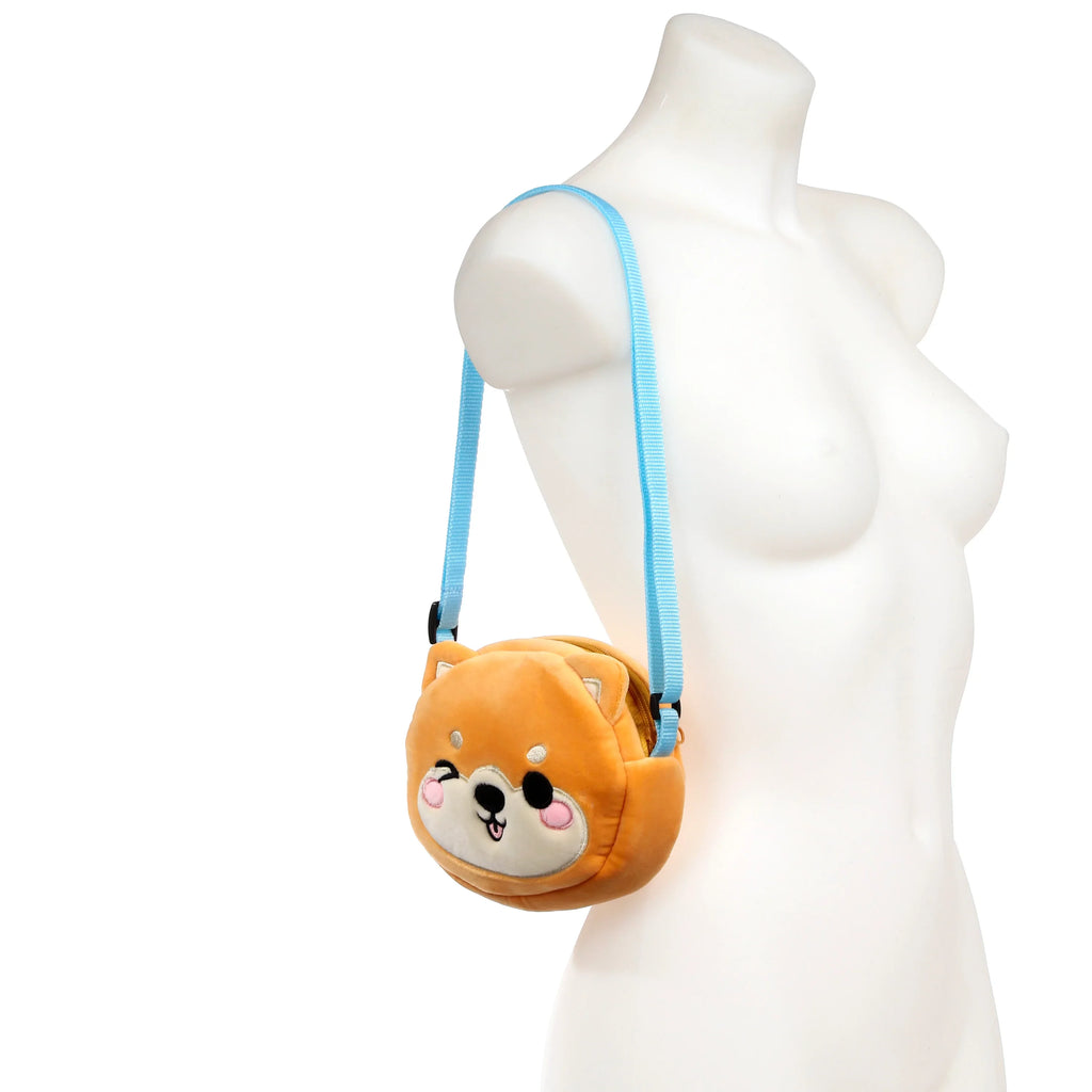 Front view of a plush Shiba Inu crossbody bag with a winking face and blue strap, displayed on a mannequin.