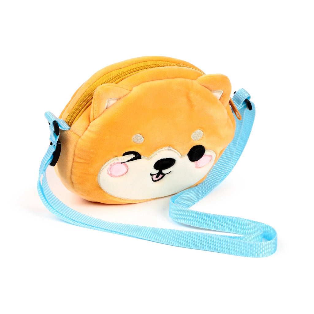 Angled front view of a plush orange Shiba Inu crossbody bag, featuring an embroidered winking face with pink cheeks and a light blue adjustable strap.