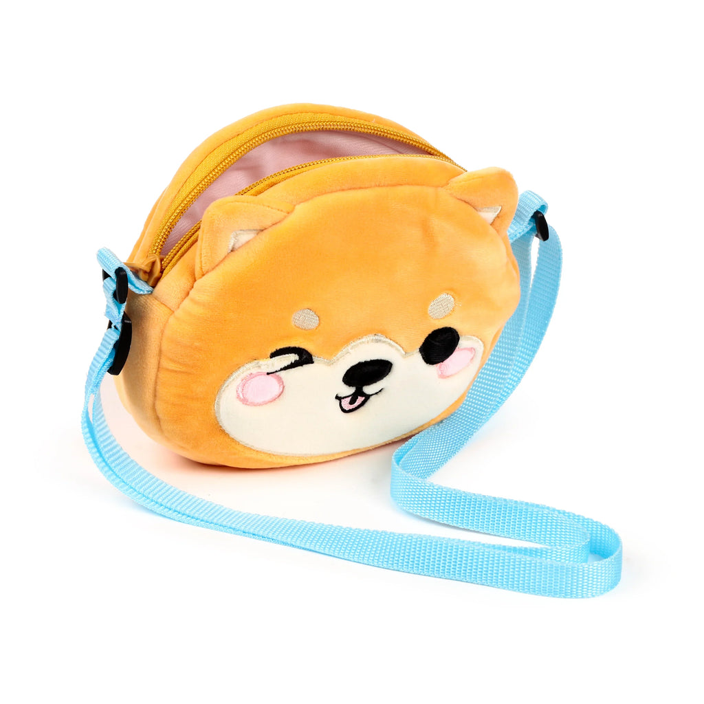 Front angled view of a plush orange Shiba Inu cross body bag with an embroidered winking face, pink cheeks, light blue shoulder strap, and an open yellow zip revealing a pink interior.