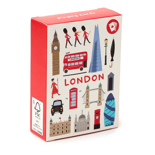 Angled view of a playing cards box, white with red sides, featuring a colourful London souvenir illustration. The design depicts iconic landmarks such as Big Ben, a red double-decker bus, and Tower Bridge, alongside Queen's Guards, with 'LONDON' text prominently displayed.