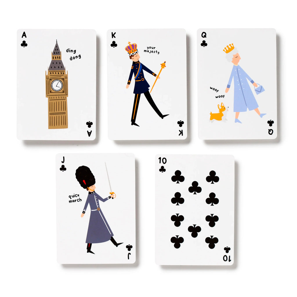 Overhead flat lay of five novelty London souvenir playing cards from the clubs suit. Visible are the Ace depicting Big Ben, the King, the Queen with a corgi, the Jack as a Royal Guard, and the Ten, all with unique cartoon illustrations.