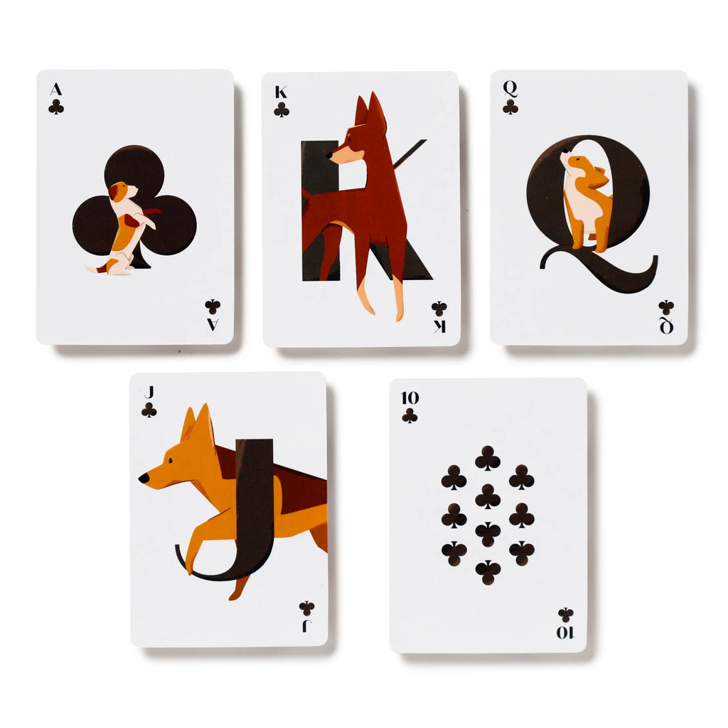 Overhead view of five white playing cards from a dog-themed deck, featuring unique canine illustrations. The visible cards include the Ace, King, Queen, and Jack of Clubs with stylised dog designs, and the Ten of Clubs displaying standard club symbols.
