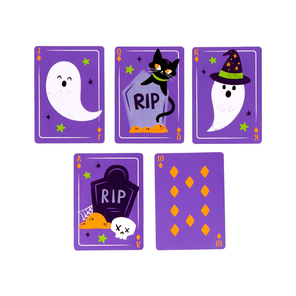 Overhead view of five purple Halloween playing cards displaying different face designs: a friendly ghost, a black cat with an 'RIP' tombstone, a ghost wearing a witch's hat, a skull with an 'RIP' tombstone, and a card with ten orange diamond pips.