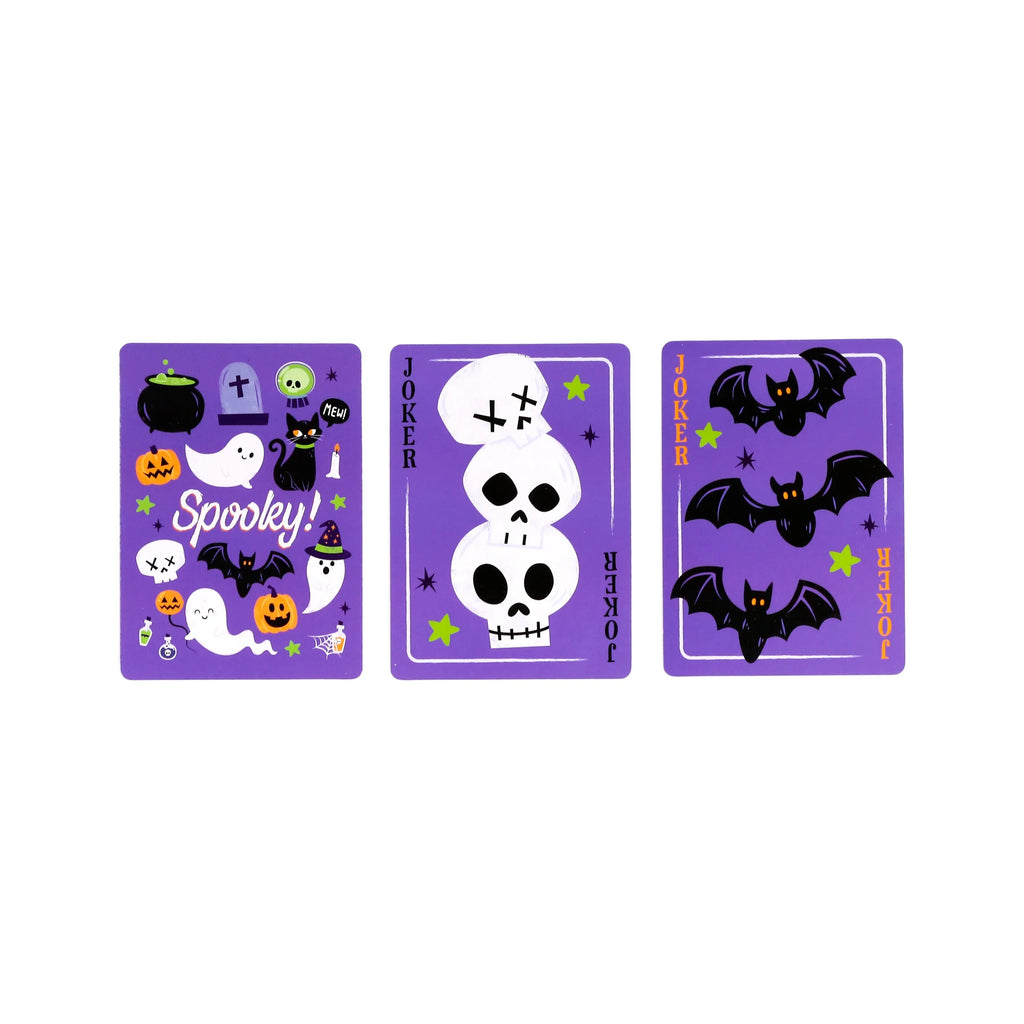 Overhead view displaying three purple 'Spooky' playing cards. One card features assorted Halloween illustrations including ghosts, jack-o'-lanterns, bats, and a black cat. The other two cards are Joker cards, depicting stacked skulls and flying bats.