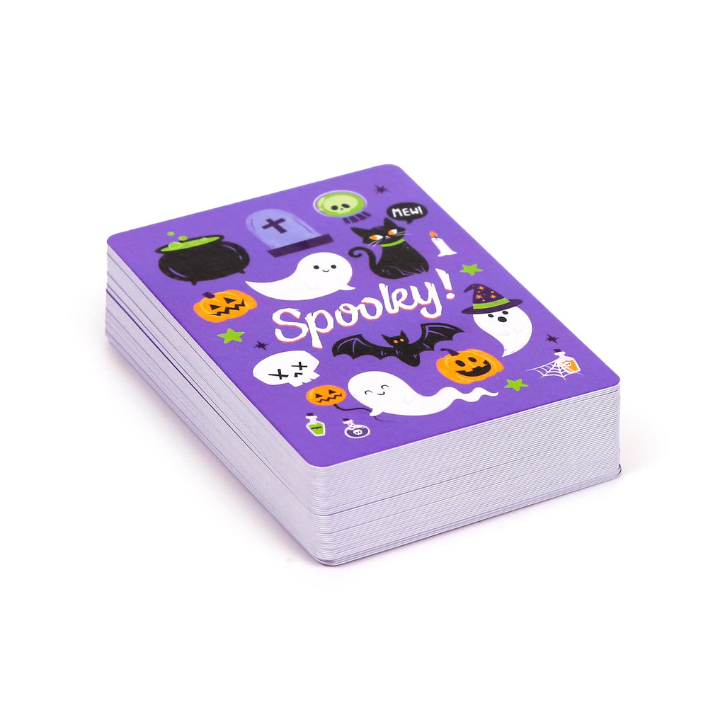 Angled view of a standard playing card deck, showing its purple Halloween back design with cartoon ghosts, pumpkins, a black cat, and the text 'Spooky!'