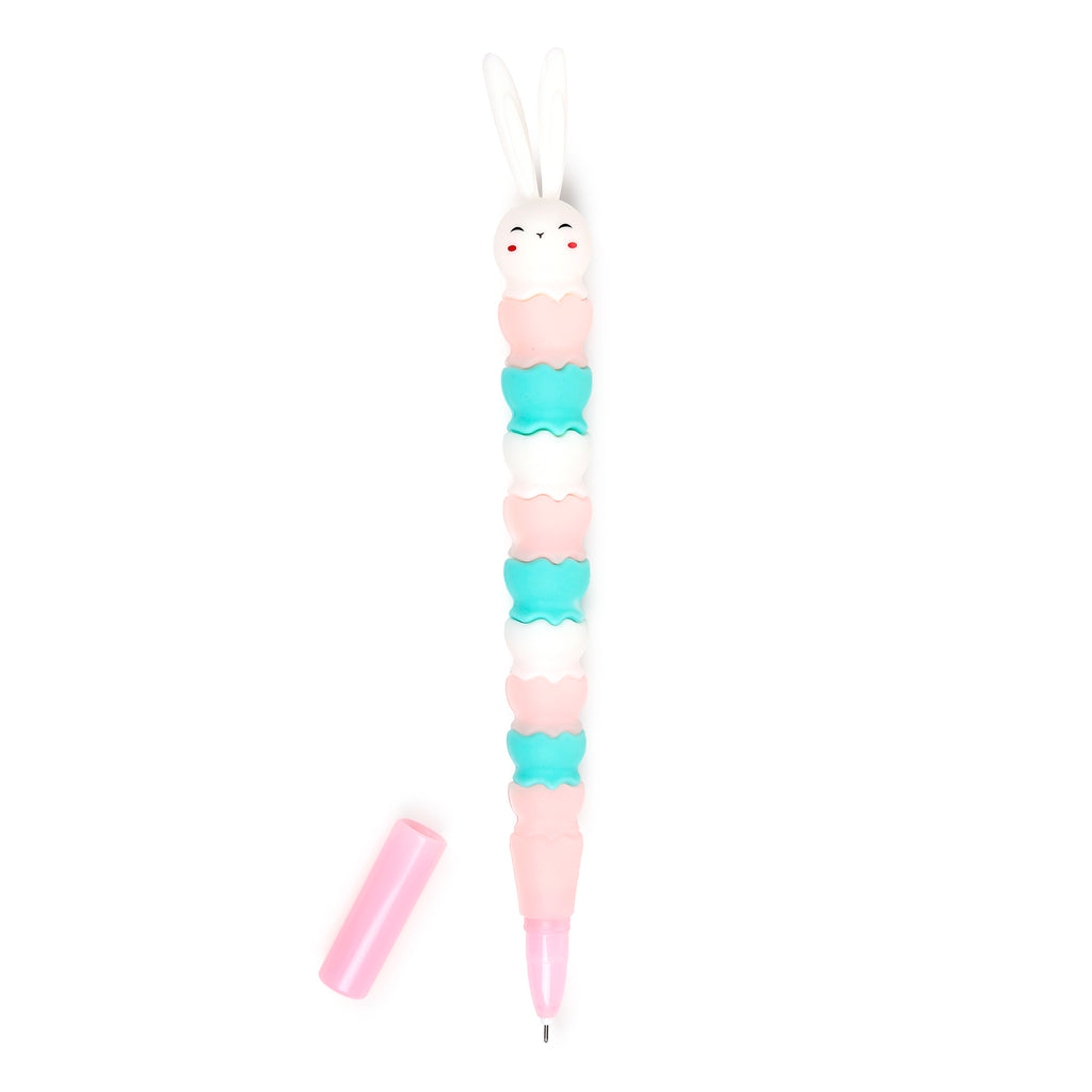 Upright view of a bunny rabbit shaped fine tip pen, featuring a white rabbit head with long ears, and a body composed of stacked pink, turquoise, and white sections with wavy edges. A matching pink cap lies beside the pen.