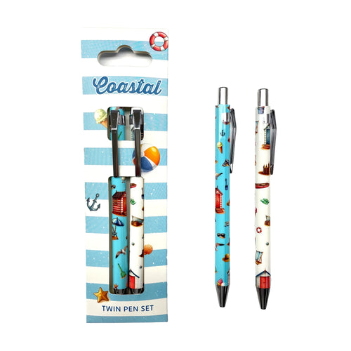 Twin pen set, front view. Blue and white striped packaging, featuring 'Coastal' text and beach illustrations, holds one pen. The second pen stands upright beside it. Both pens display coastal-themed patterns of beach huts, anchors, and seashells, with one predominantly blue and the other white, all with silver-coloured clips.