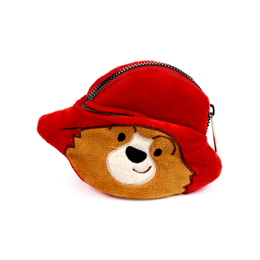 Angled view of a plush Paddington Bear change purse, featuring a red hat, brown fur, white muzzle, black eyes, nose, and a black zipper.