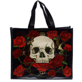 Front view of a black reusable shopping tote bag, featuring a gothic-style design with a central pale skull surrounded by vibrant red roses, a moth, a bird, and golden mystical symbols.