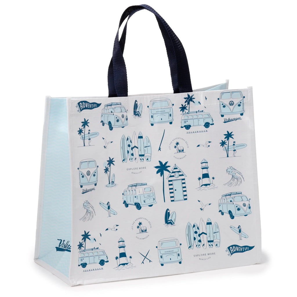 Angled view of a white recycled RPET reusable shopping bag, adorned with blue illustrations of Volkswagen T1 camper buses, lighthouses, palm trees, surfers, surfboards, waves, and seagulls. Visible text includes 'ADVENTURE' and 'EXPLORE MORE'. The bag features dark blue fabric handles and light blue wavy side panels.