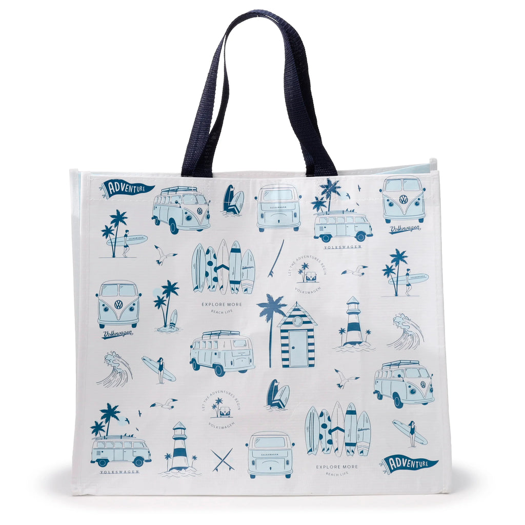 Front view of a white reusable shopping bag with dark blue fabric handles, decorated with a blue illustrated pattern featuring Volkswagen T1 camper buses, surfboards, palm trees, lighthouses, beach huts, and text like 'ADVENTURE' and 'EXPLORE MORE BEACH LIFE'.