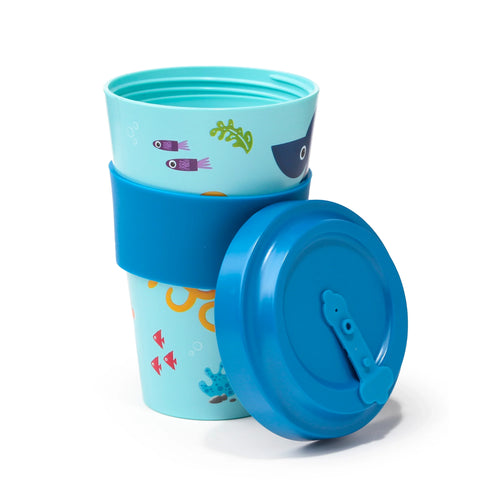 Angled view of a light blue travel mug with colourful sealife illustrations, featuring a dark blue silicone grip band and a separate dark blue flip-top lid.
