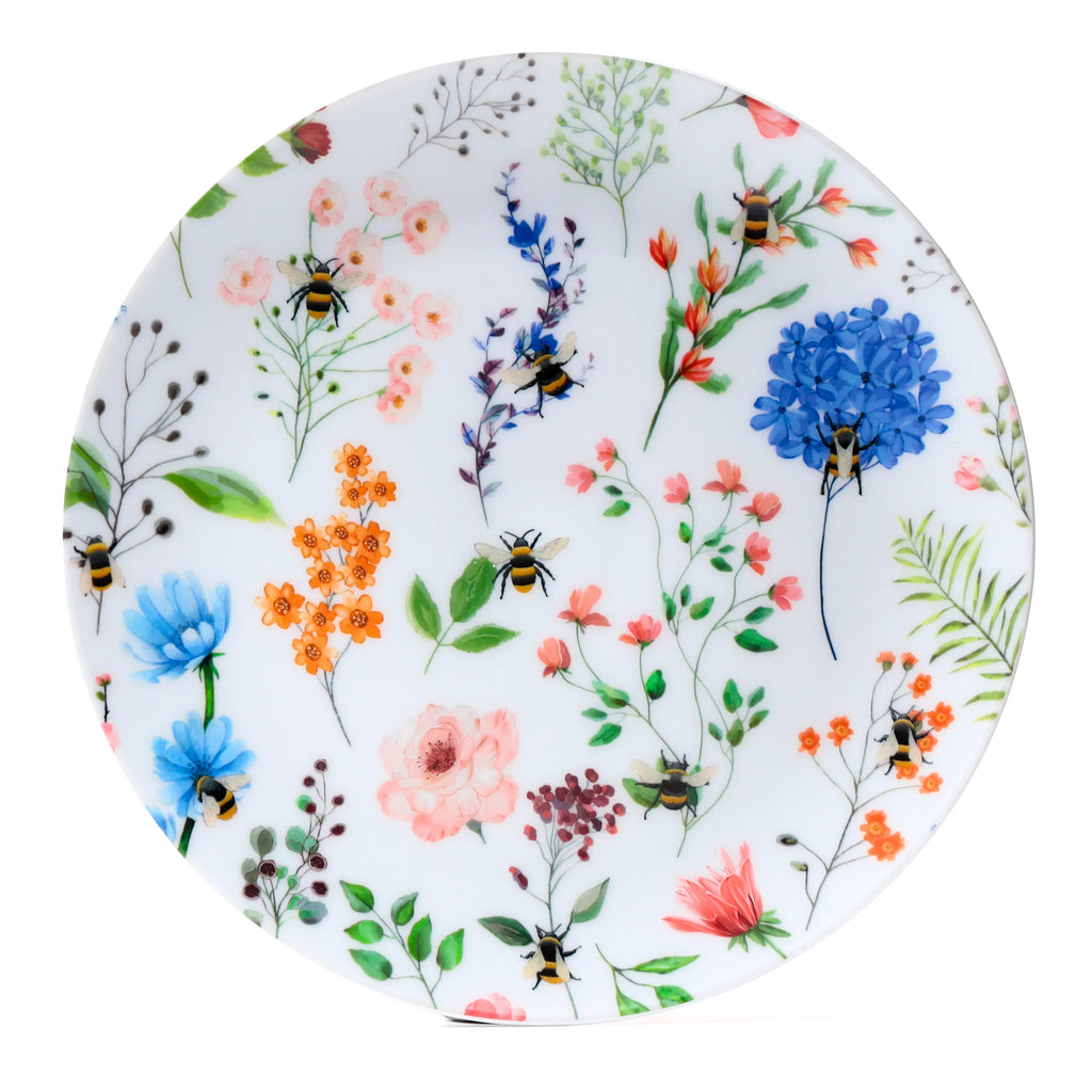 Top view of a circular picnic plate, featuring a vibrant Nectar Meadows design with pink, blue, and orange flowers, green foliage, and bumblebees.