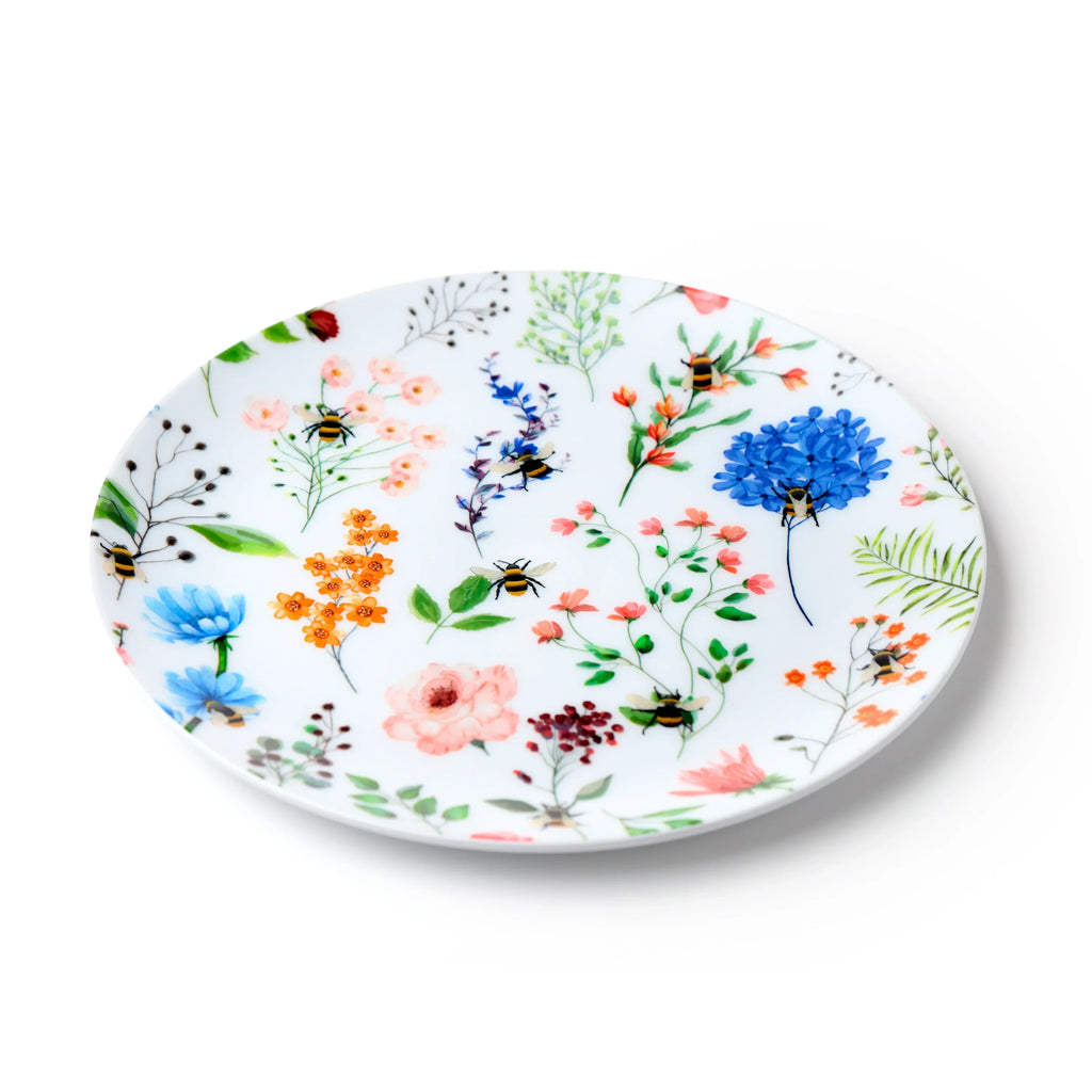 Angled view of a round white picnic plate with a 'Nectar Meadows' design, featuring vibrant multi-coloured flowers and bumblebees.