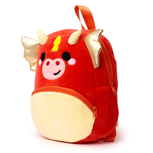 Front 3/4 view of a red kids dragon school backpack featuring gold wings, light yellow horns, and a cartoon face. It has orange zippers and a light yellow bottom pocket.