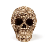 Front view of a cream-coloured multiple skulls head decoration, an ornament shaped like a large skull intricately covered with numerous smaller skulls and skeletal details.