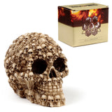 Angled view of a beige skull ornament, intricately formed from many smaller skulls and bone details. A patterned display box, labelled 'SKULL ORNAMENT', is visible in the background.