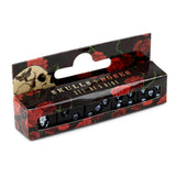 Angled view of a black skull dice set, packaged in a black box adorned with red roses and a skull motif. Five black dice, each featuring a white skull design, are visible through the clear front window of the packaging, which also includes a hang tab.