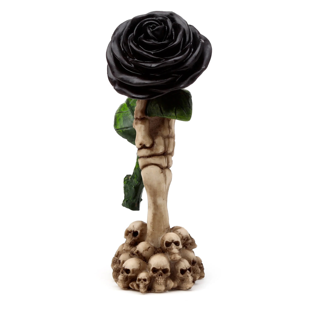 Front view of a Gothic skull decoration ornament, featuring a bone-coloured skeleton hand holding a black rose with sculpted petals and green leaves, set atop a base of piled skulls.