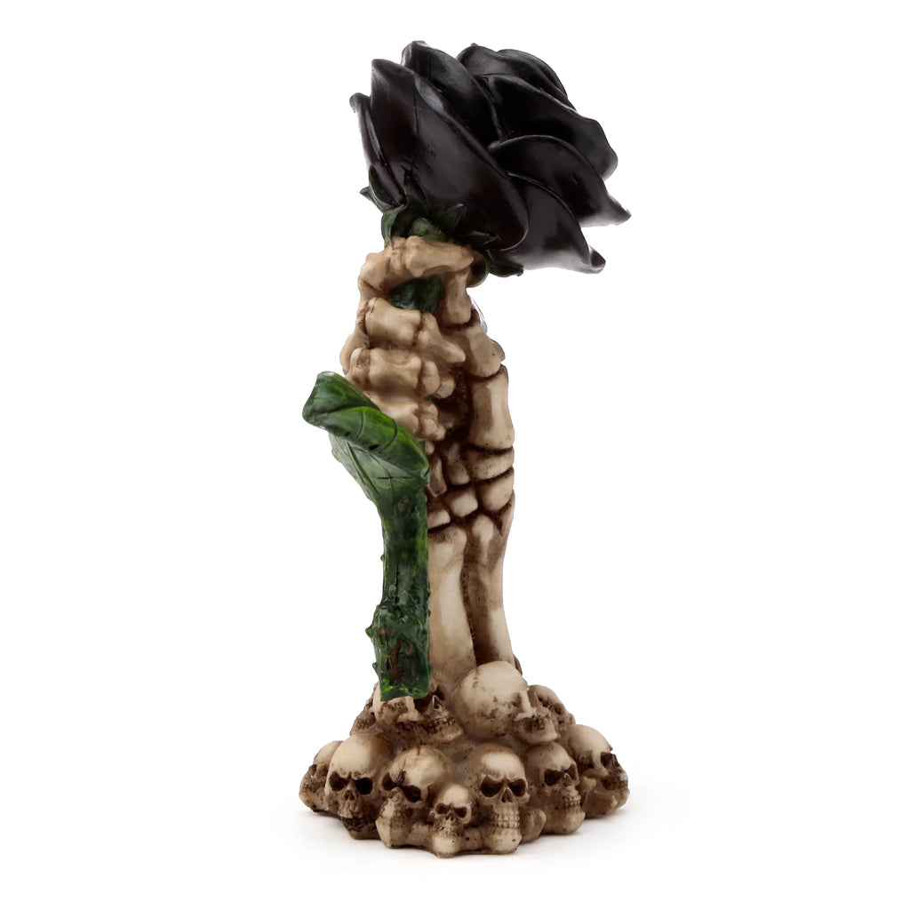Full view of a gothic skull ornament featuring a black rose with green leaves held by a bone-coloured skeletal hand, atop a base of skulls.