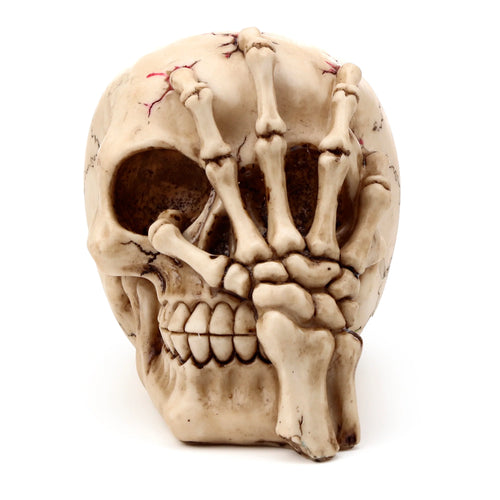 Angled view of a bone-coloured gothic skull head decoration with red cracks and dark crevices, featuring a skeleton claw hand covering the eye sockets.